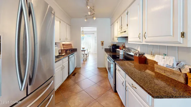 a kitchen with stainless steel appliances granite countertop a refrigerator a sink and white cabinets