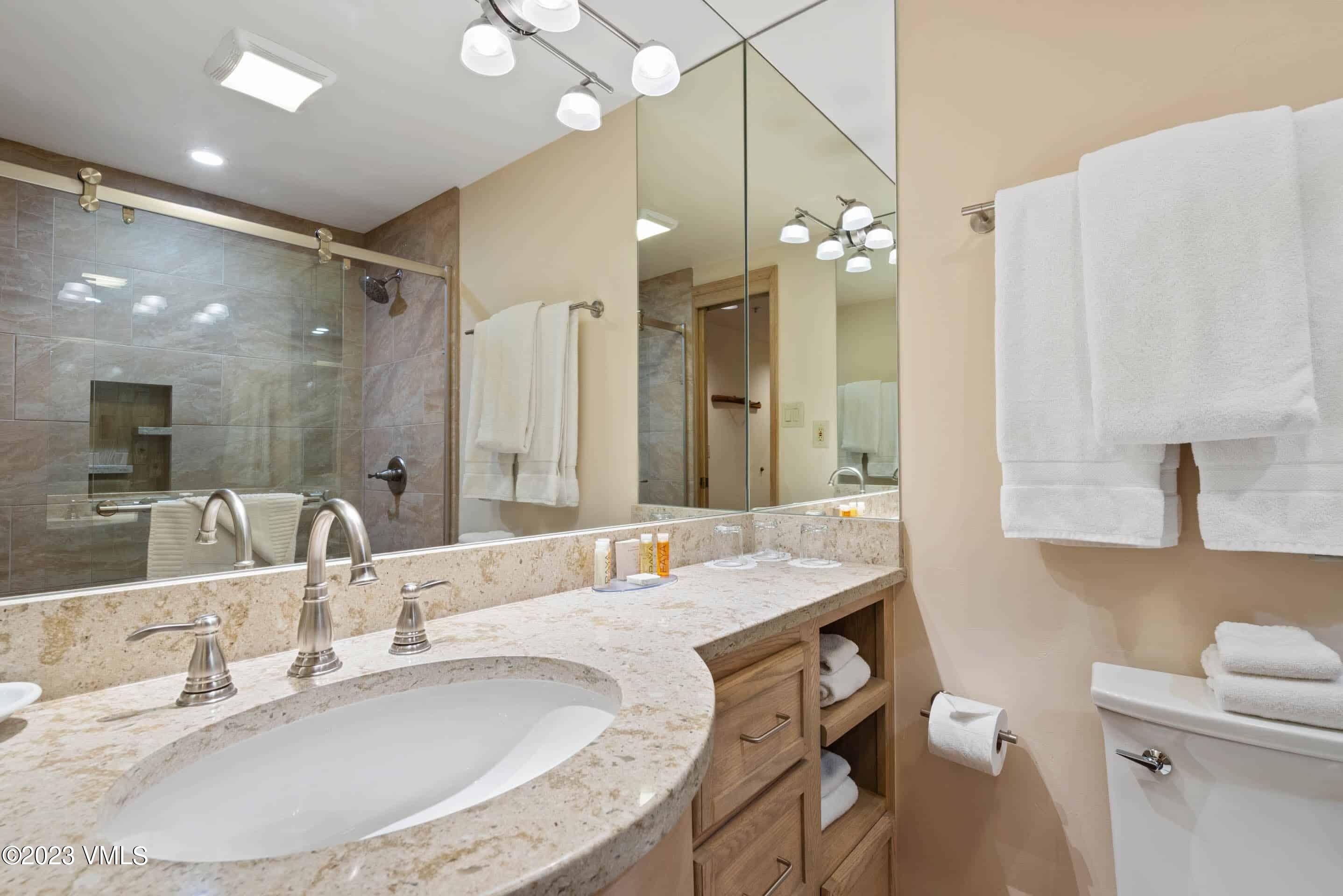 200 Vail Road, Unit 287 Vail, CO 81657 - Photo 21 of 21 a bathroom with a granite countertop sink a toilet a large mirror and shower