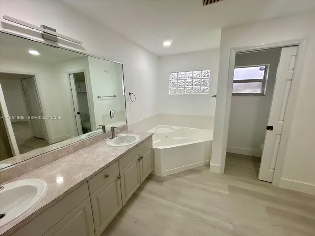 a spacious bathroom with a granite countertop sink mirror and a bathtub