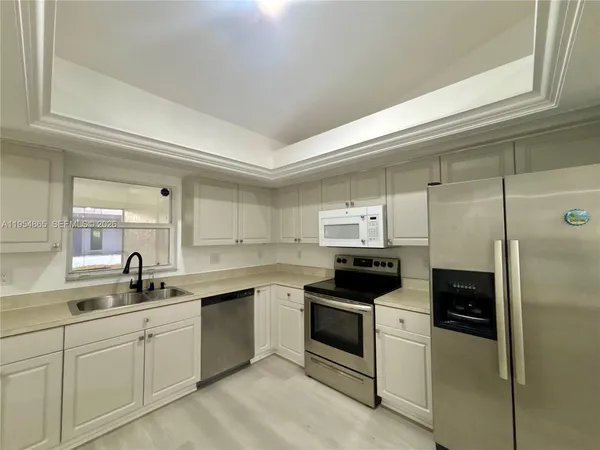 a kitchen with a sink white cabinets and stainless steel appliances