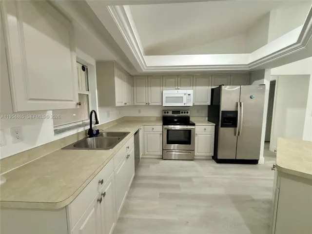 a large kitchen with a refrigerator and a sink