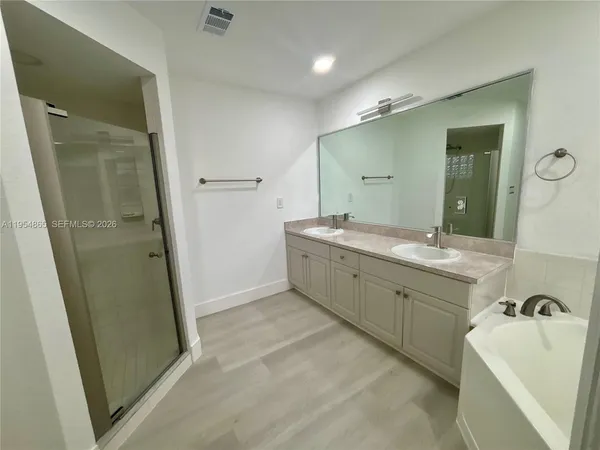 a spacious bathroom with a double vanity sink a mirror and a bathtub