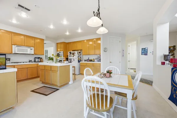 a kitchen with a dining table chairs sink and white appliances