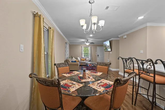 a view of a dining room with furniture a chandelier and wooden floor