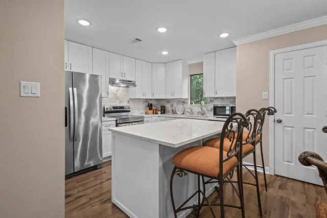 a kitchen with stainless steel appliances granite countertop a table chairs sink refrigerator and microwave