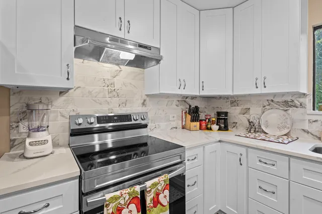a kitchen with white cabinets and appliances