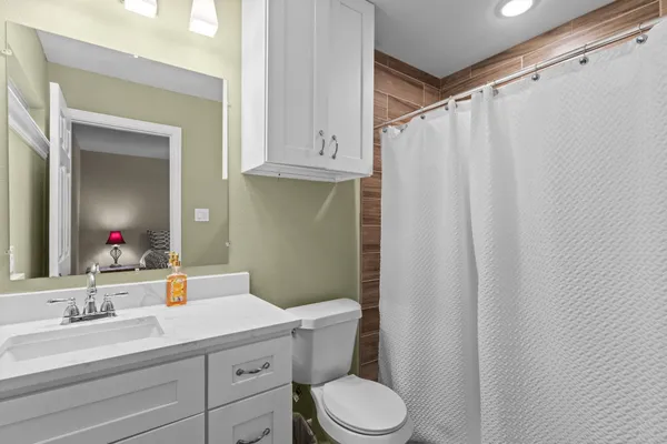 a bathroom with a sink a toilet a mirror and shower curtain