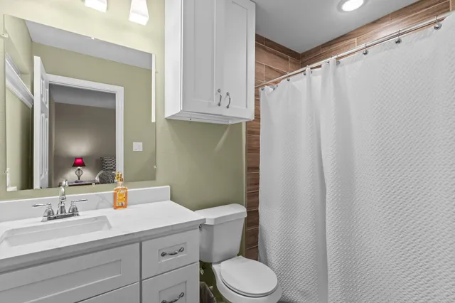 a bathroom with a sink a toilet a mirror and shower curtain