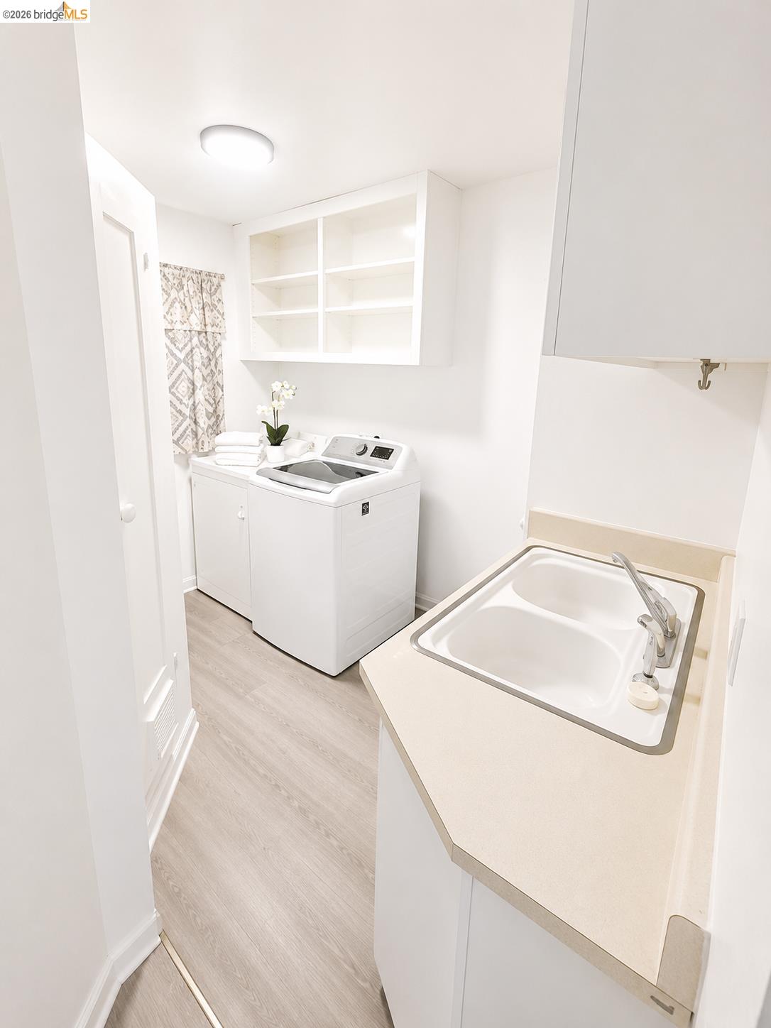 810 Pierce Street Albany, CA 94706 - Photo 19 of 25 Dedicated laundry area featuring a utility sink with a light-toned countertop, wood-finish flooring, and white cabinetry