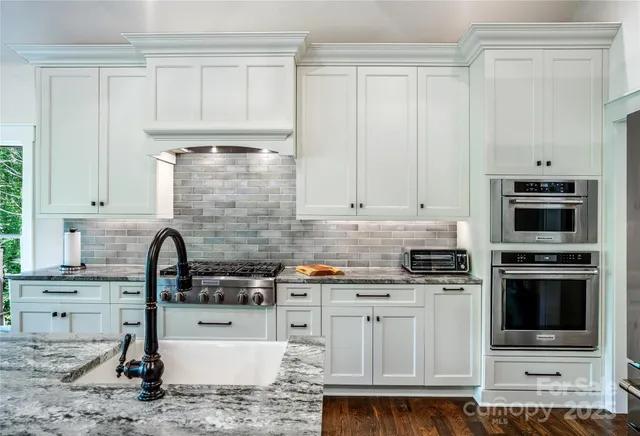 a kitchen with stainless steel appliances granite countertop a stove a sink and a microwave