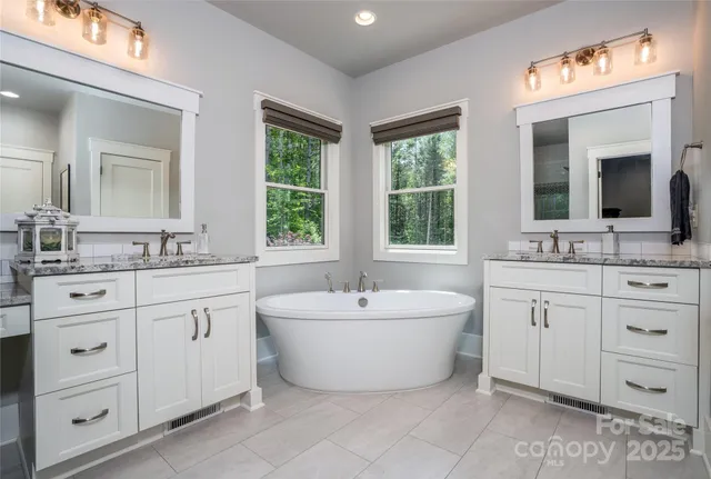 a spacious bathroom with double vanity a mirror a window and a bathtub
