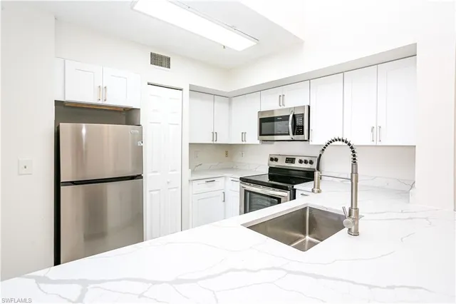 a kitchen with a refrigerator sink and wooden cabinets