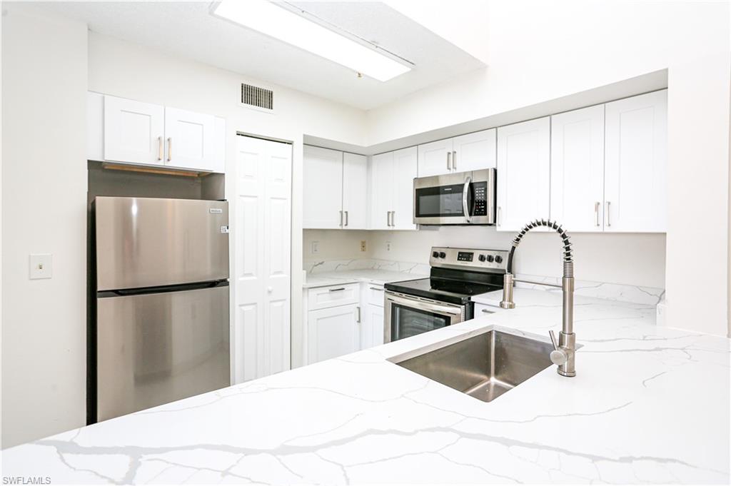 a kitchen with a refrigerator sink and wooden cabinets