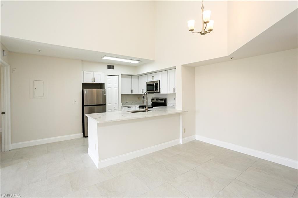 1265 Wildwood Lakes Boulevard, Unit 3306 Naples, FL 34104 - Photo 14 of 39 a kitchen with stainless steel appliances a refrigerator and a stove top oven