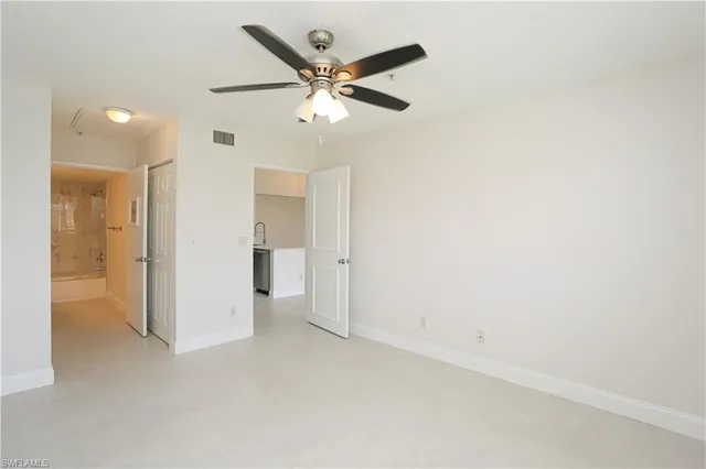 an empty room with closet and a ceiling fan