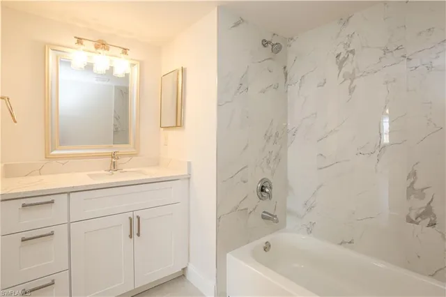 a bathroom with a granite countertop sink a mirror a bathtub and shower