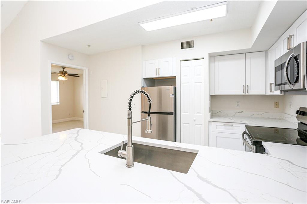 1265 Wildwood Lakes Boulevard, Unit 3306 Naples, FL 34104 - Photo 5 of 39 a kitchen with stainless steel appliances kitchen island sink refrigerator and stove