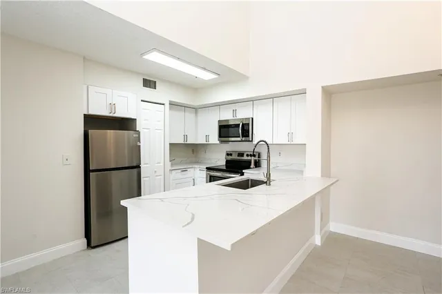 a kitchen with a refrigerator a microwave a sink and cabinets