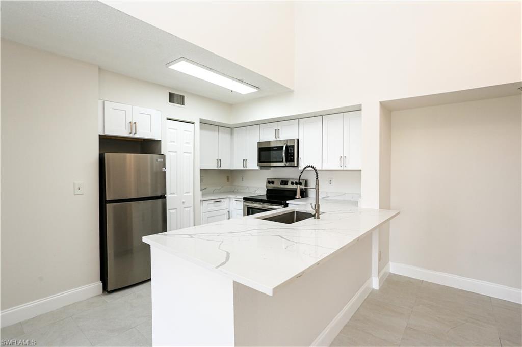 1265 Wildwood Lakes Boulevard, Unit 3306 Naples, FL 34104 - Photo 6 of 39 a kitchen with a refrigerator a microwave a sink and cabinets