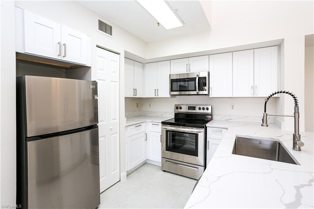 1265 Wildwood Lakes Boulevard, Unit 3306 Naples, FL 34104 - Photo 8 of 39 a kitchen with a refrigerator sink and microwave