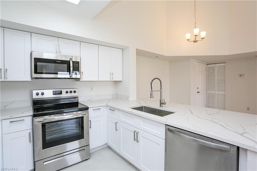 1265 Wildwood Lakes Boulevard, Unit 3306 Naples, FL 34104 - Photo 9 of 39 a kitchen with white cabinets stainless steel appliances and sink