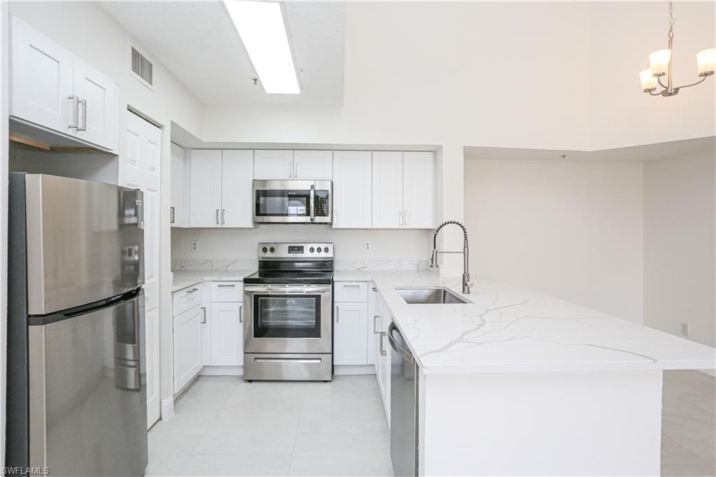 1265 Wildwood Lakes Boulevard, Unit 3306 Naples, FL 34104 - Photo 10 of 39 a kitchen with a refrigerator sink and white stove