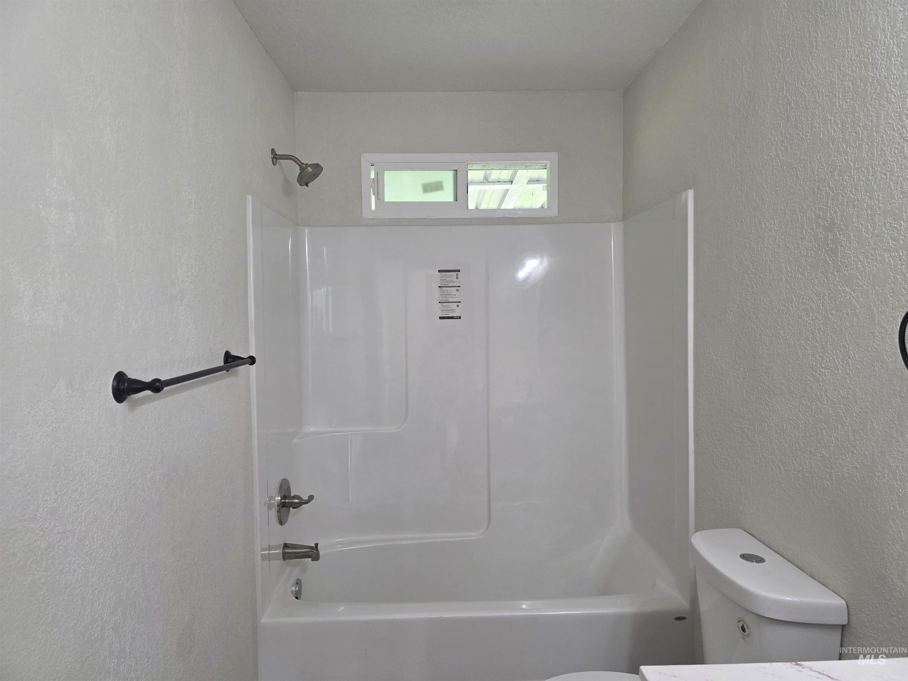 310 Fir Road Kamiah, ID 83536 - Photo 24 of 32 White tub-shower combination with a textured wall surround and an overhead transom window