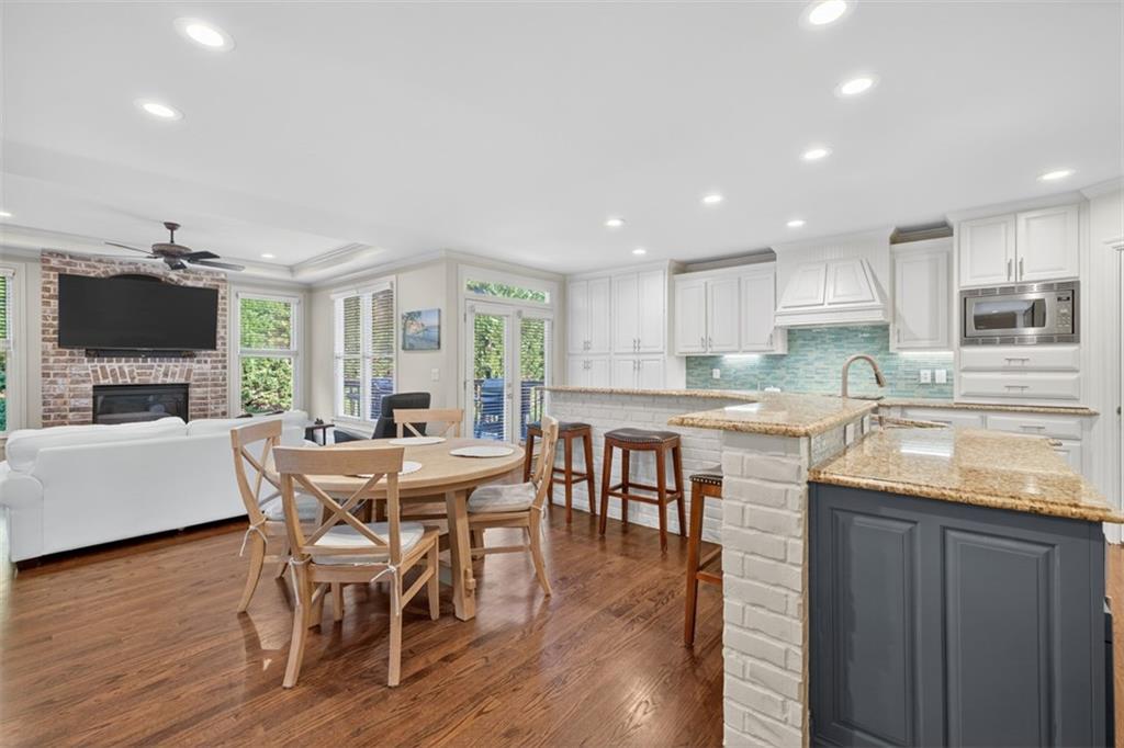 909 Pathview Court Dacula, GA 30019 - Photo 21 of 113 a kitchen with stainless steel appliances granite countertop a stove top oven a sink dishwasher a dining table and chairs with wooden floor