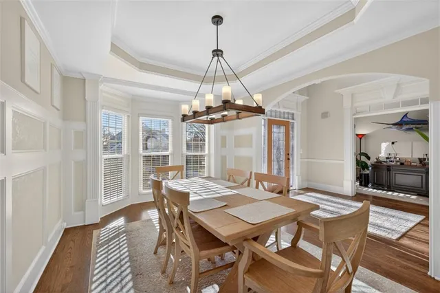 a kitchen with stainless steel appliances granite countertop a stove top oven a sink dishwasher a dining table and chairs with wooden floor