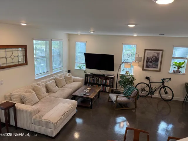 a living room with furniture a flat screen tv and a large window