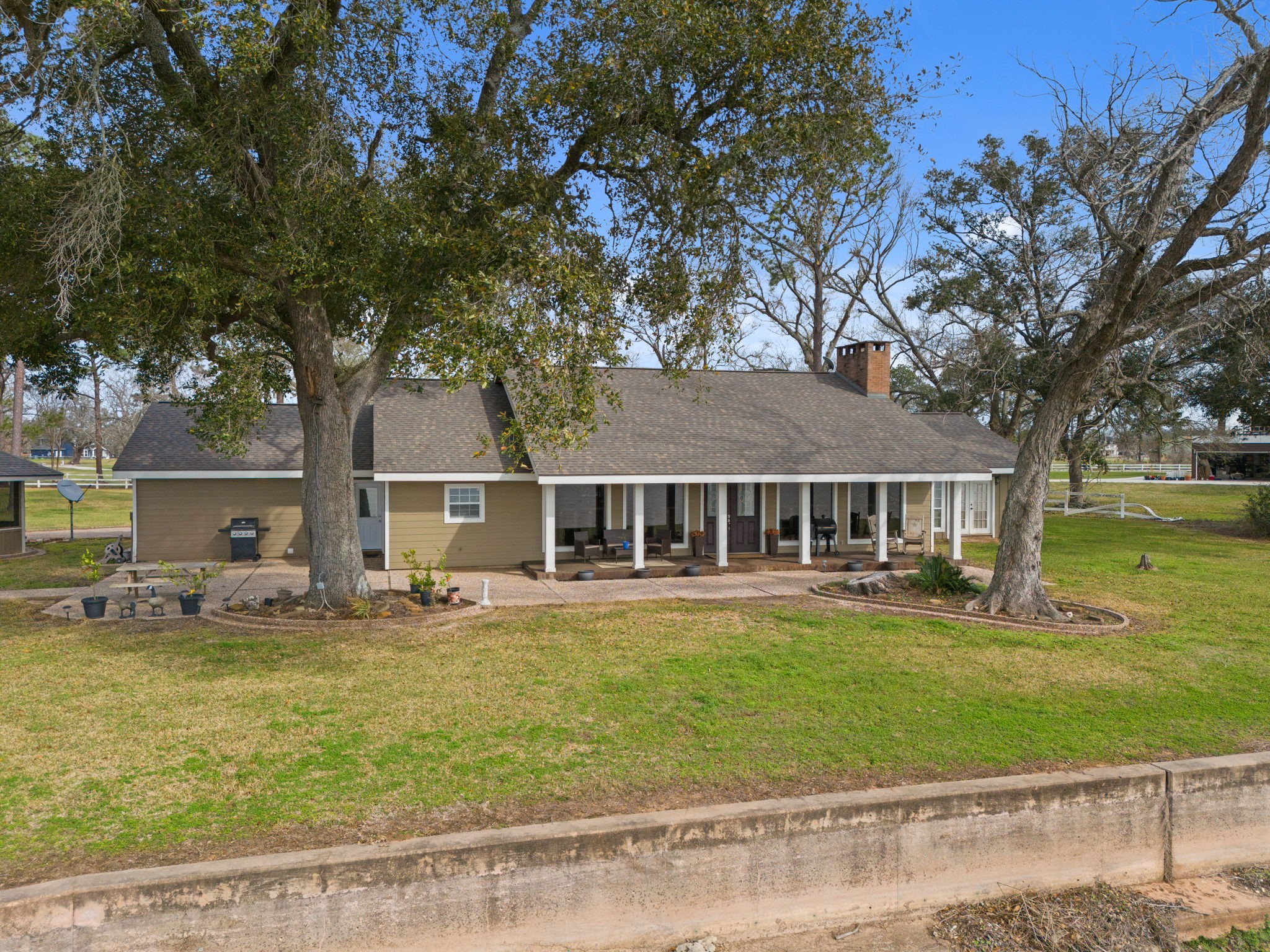 2935 West Fm 1462 Rosharon, TX 77583 - Photo 11 of 50 This wide, open view highlights the airy, peaceful feel of the ranch homestead. The long, covered porch stretches across the front of the house, reinforcing a sense of openness and easy indoor-outdoor living.