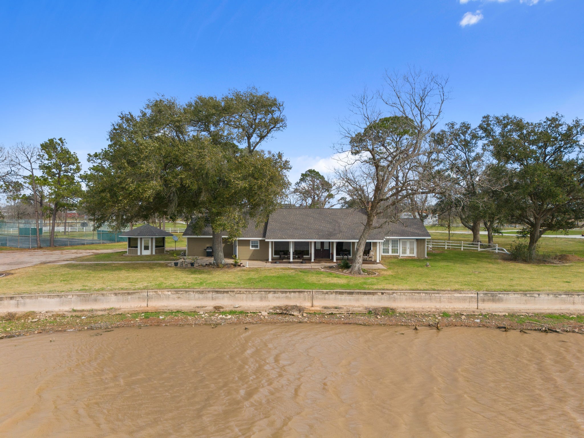 2935 West Fm 1462 Rosharon, TX 77583 - Photo 12 of 50 This sweeping view captures the ranch home set gracefully along the water’s edge, framed by mature shade trees and wide open lawn.