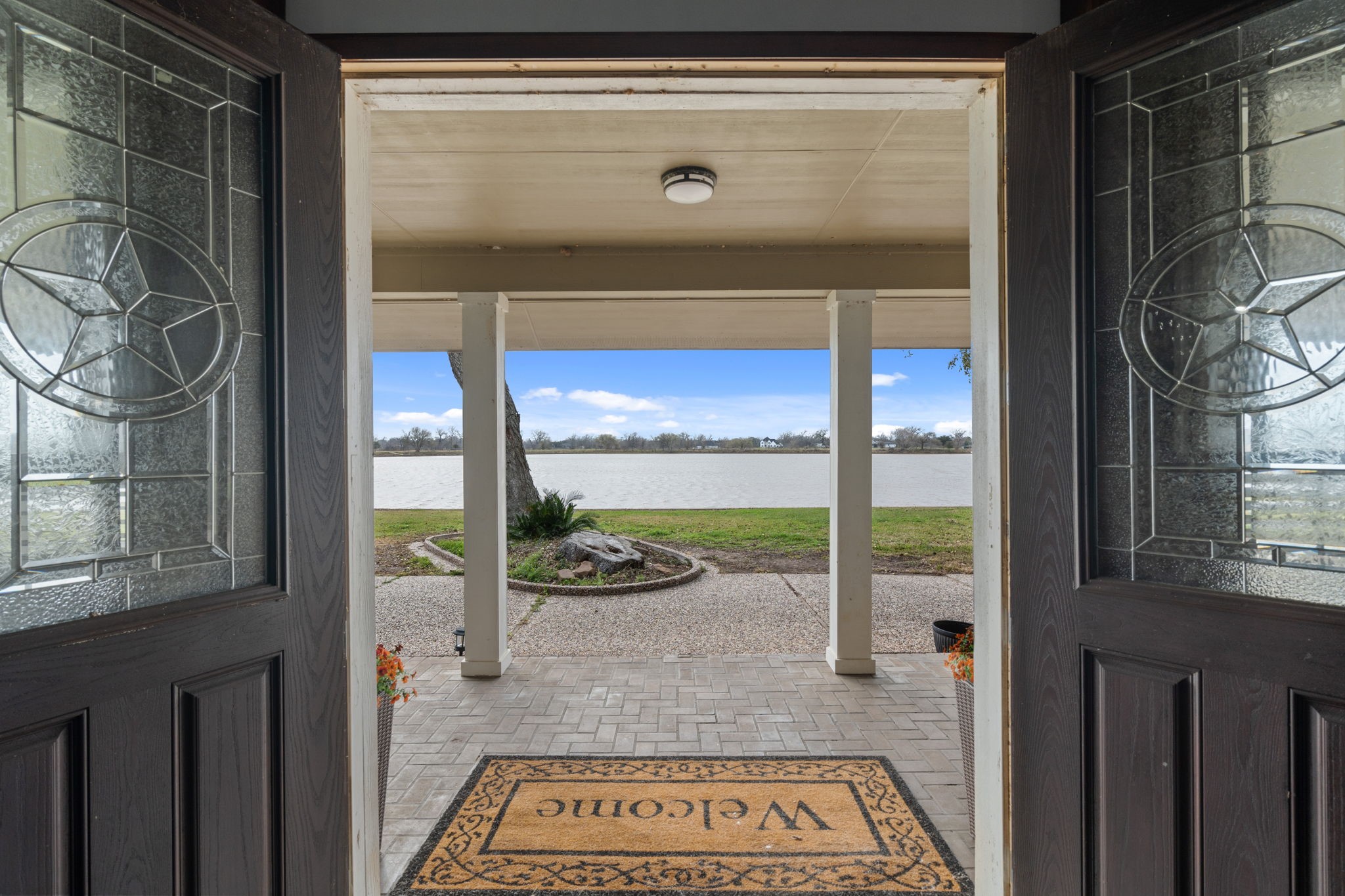 2935 West Fm 1462 Rosharon, TX 77583 - Photo 13 of 50 This welcoming entry frames a beautiful view from inside the home straight out to the lake beyond. Double doors open to a covered porch, where the eye is drawn across the landscaped walkway and open lawn to the calm water stretching across the horizon.
