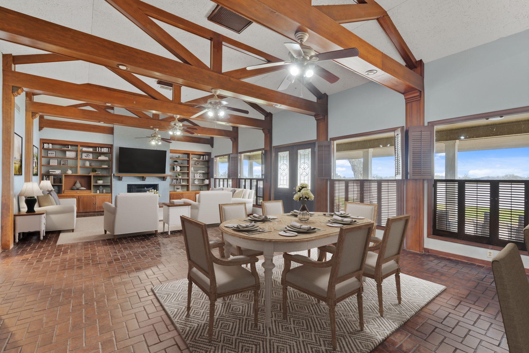 2935 West Fm 1462 Rosharon, TX 77583 - Photo 16 of 50 Virtually Staged: The space flows seamlessly into the dining area and kitchen beyond, creating a natural hub for family meals, entertaining, and hosting after long days outdoors—perfectly capturing the ease and scale of true ranch-style living. Large windows with wood shutters frame peaceful outdoor views, reinforcing the home’s strong connection to its ranch setting.