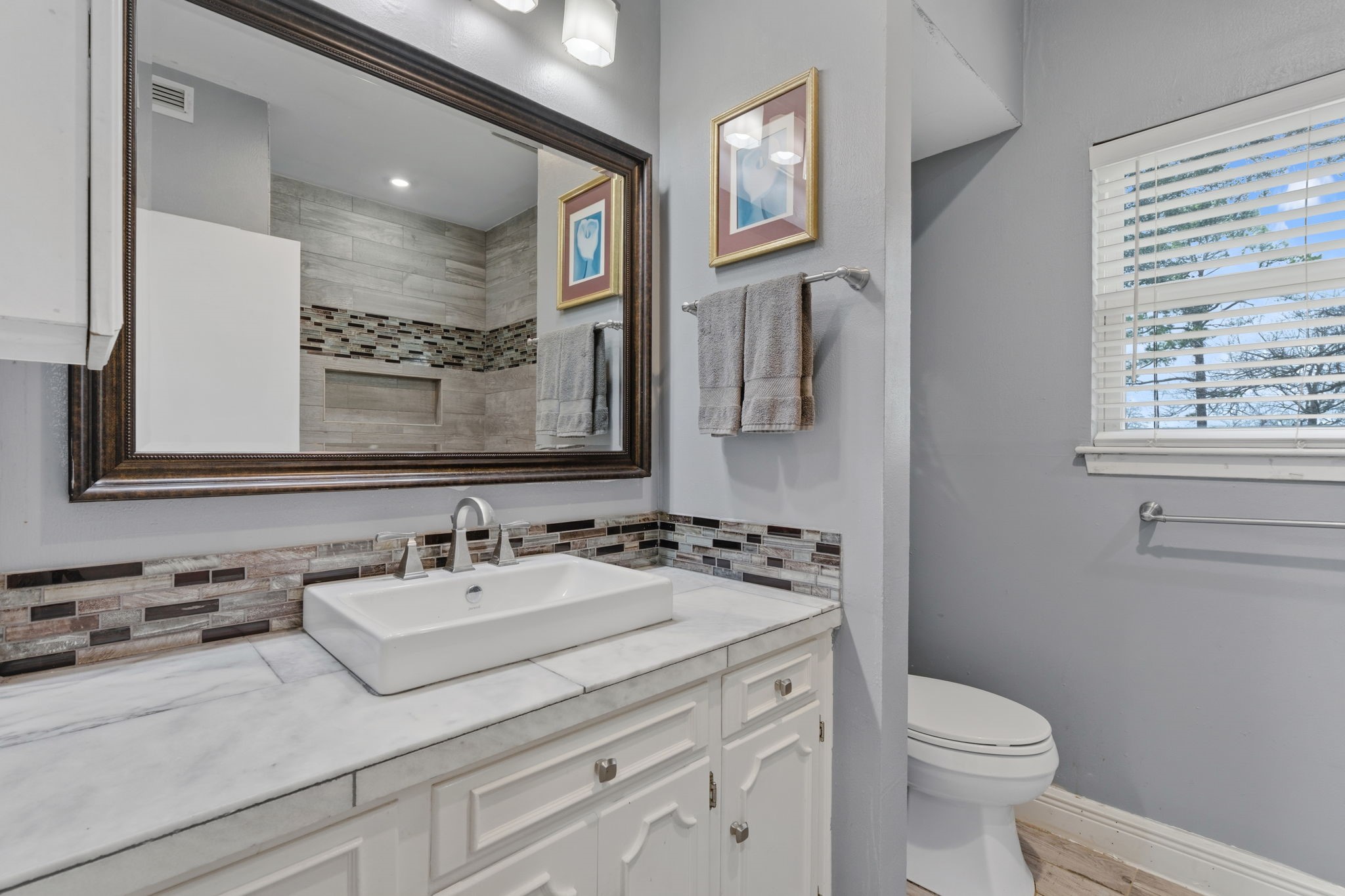 2935 West Fm 1462 Rosharon, TX 77583 - Photo 27 of 50 This photo highlights a refined bathroom vanity area with a clean, modern aesthetic. A rectangular vessel sink sits atop a tile-accented countertop, paired with sleek fixtures and ample cabinetry below for storage.