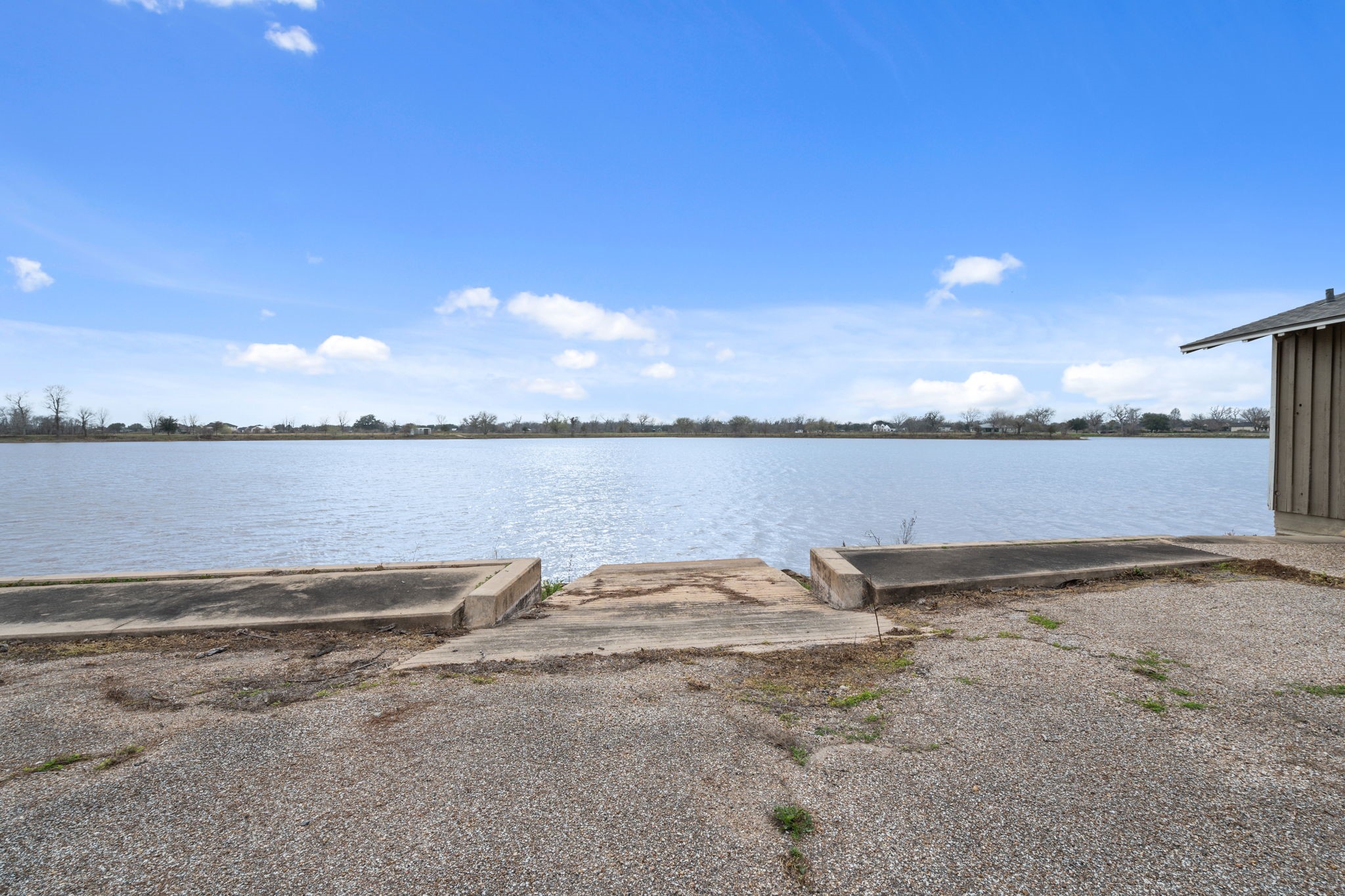 2935 West Fm 1462 Rosharon, TX 77583 - Photo 50 of 50 This serene lakeside view captures the quiet beauty of open water stretching to the horizon beneath a wide Texas sky. A concrete launch or shoreline access point gently meets the water’s edge, offering a practical and peaceful transition from land to lake.