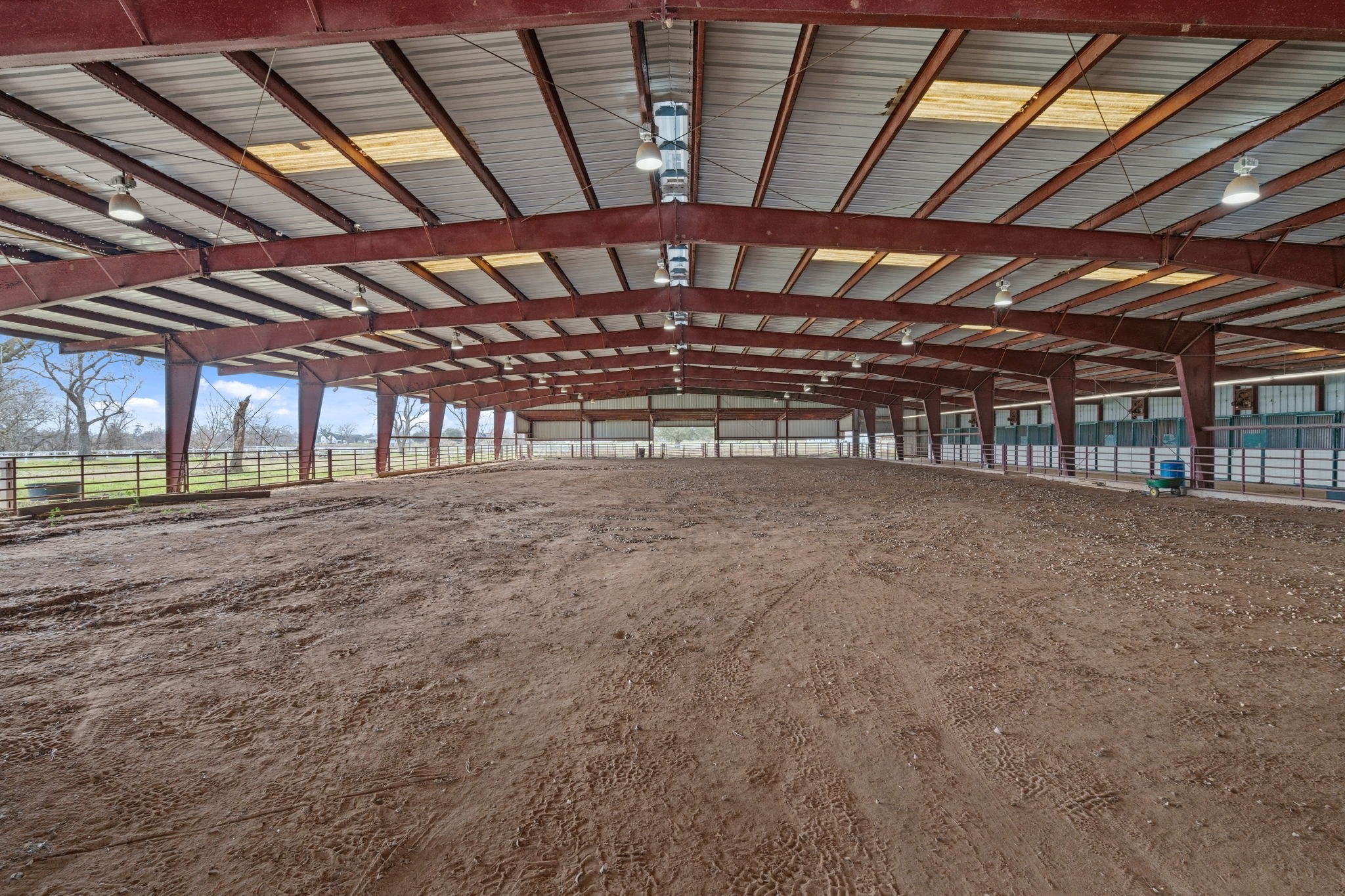 2935 West Fm 1462 Rosharon, TX 77583 - Photo 5 of 50 This expansive covered riding arena is currently set up for equestrian use, offering a versatile and functional space for training, riding, and daily horse care. The wide-open interior provides ample room for riding patterns, groundwork, and conditioning, while the steel-beam structure and high roof allow for excellent airflow and natural light.