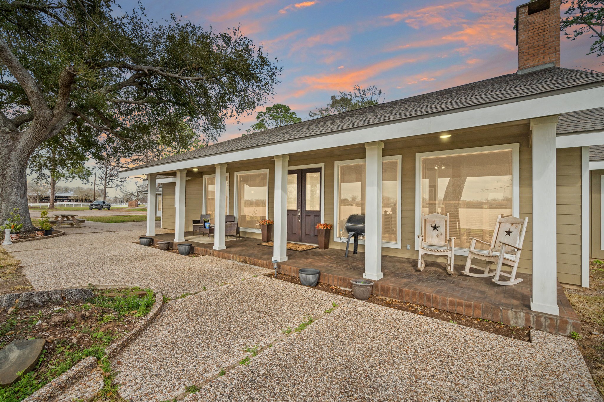 2935 West Fm 1462 Rosharon, TX 77583 - Photo 9 of 50 Large windows line the front elevation, bringing natural light inside while maintaining a strong connection to the land. The centered double-door entry adds a touch of character and balance, while the chimney and low-pitched roofline reinforce the home’s timeless ranch design.