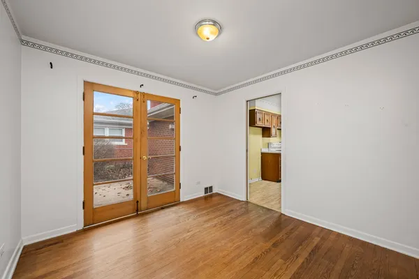 a view of an empty room with wooden floor and fan