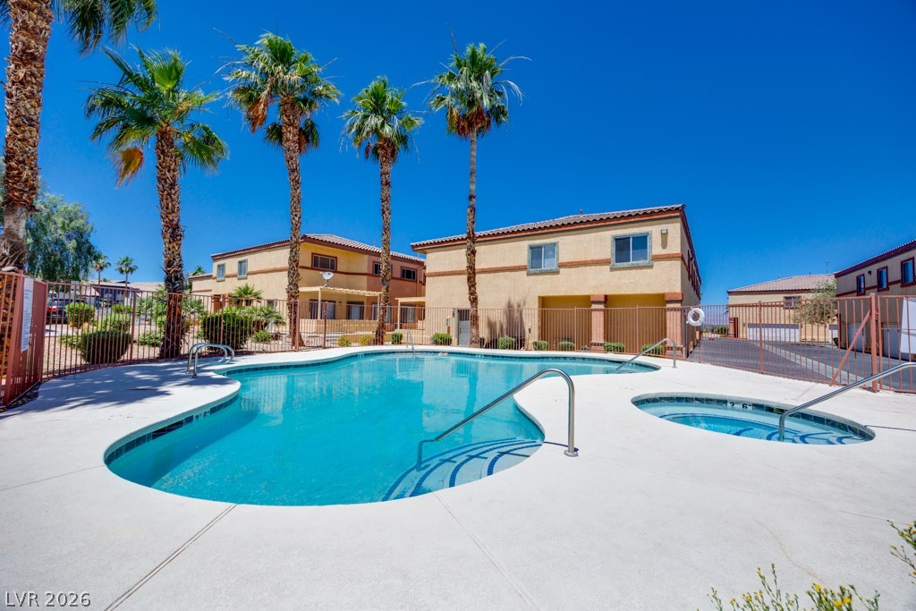 4915 East Russell Road, Unit 127 Las Vegas, NV 89120 - Photo 2 of 19 A refreshing pool and spa area with a vibrant blue sky, surrounded by palm trees and residential buildings.