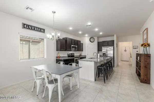 a kitchen with stainless steel appliances granite countertop a stove top oven a sink a dining table and chairs