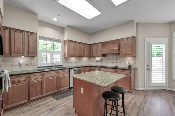 a kitchen with stainless steel appliances granite countertop wooden floors a stove a sink and a window