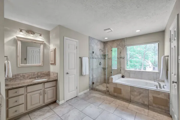 a spacious bathroom with a granite countertop tub sink shower and mirror