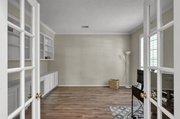 a view of an empty room with wooden floor and a window