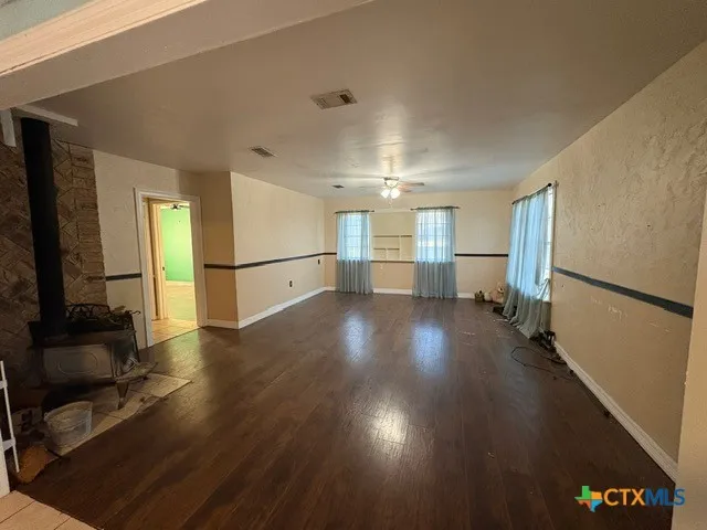 a view of a big room with wooden floor and windows