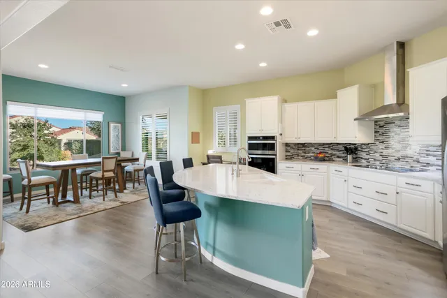 a kitchen with stainless steel appliances granite countertop a stove a refrigerator a kitchen island a couches and chairs with wooden floor