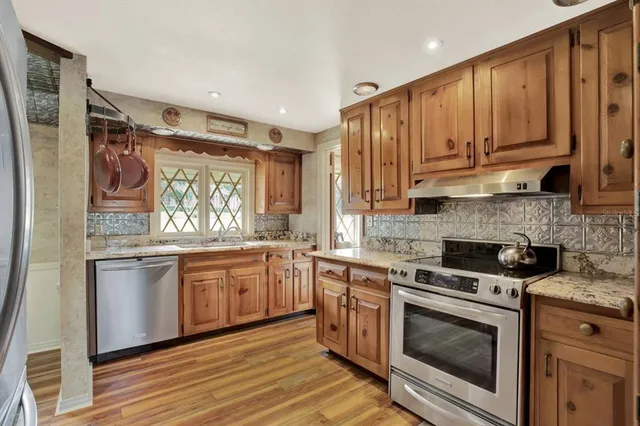 a kitchen with stainless steel appliances granite countertop a stove and white cabinets