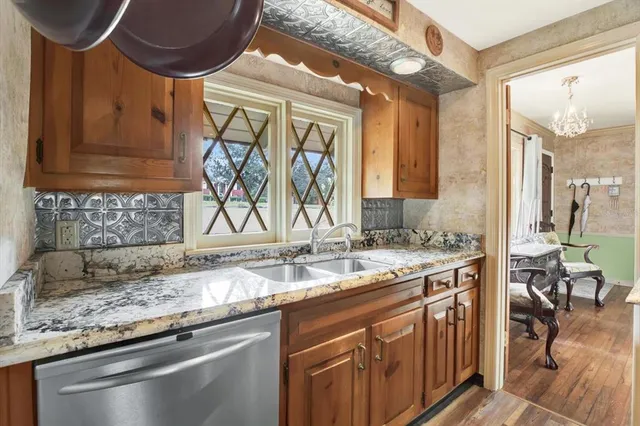 a kitchen with stainless steel appliances granite countertop a sink a stove and a wooden cabinets