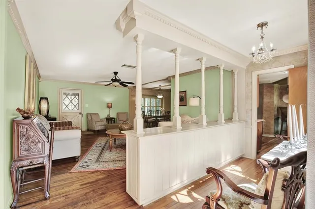 a living room with furniture a chandelier and wooden floor