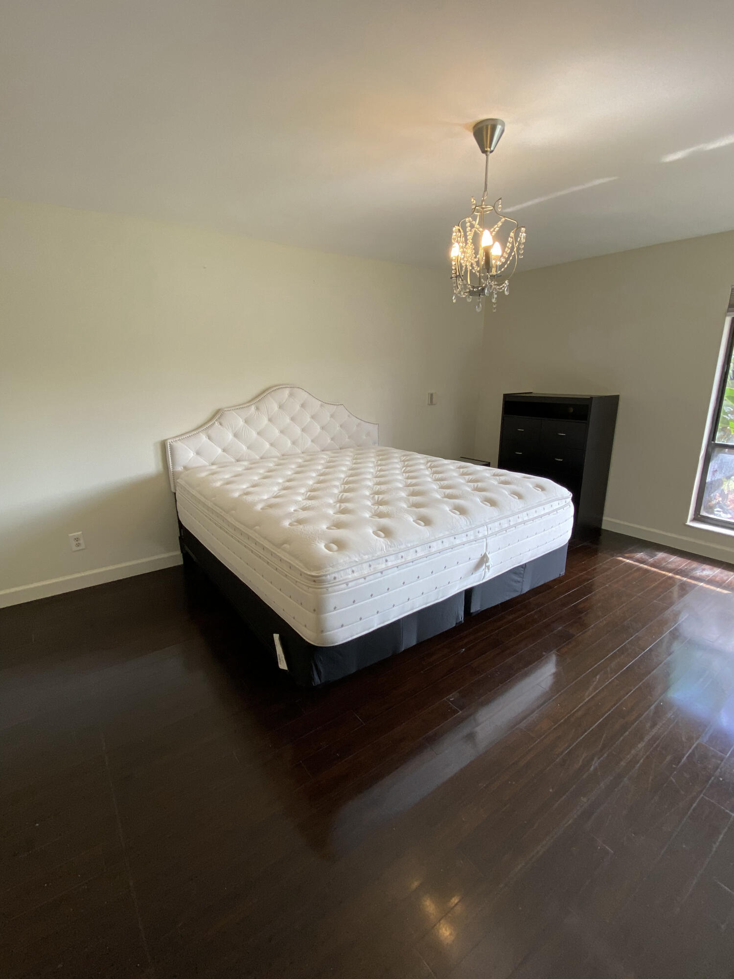 5621 Coach House Circle, Unit D Boca Raton, FL 33486 - Photo 28 of 29 a bed sitting in a spacious bedroom next to a chandelier